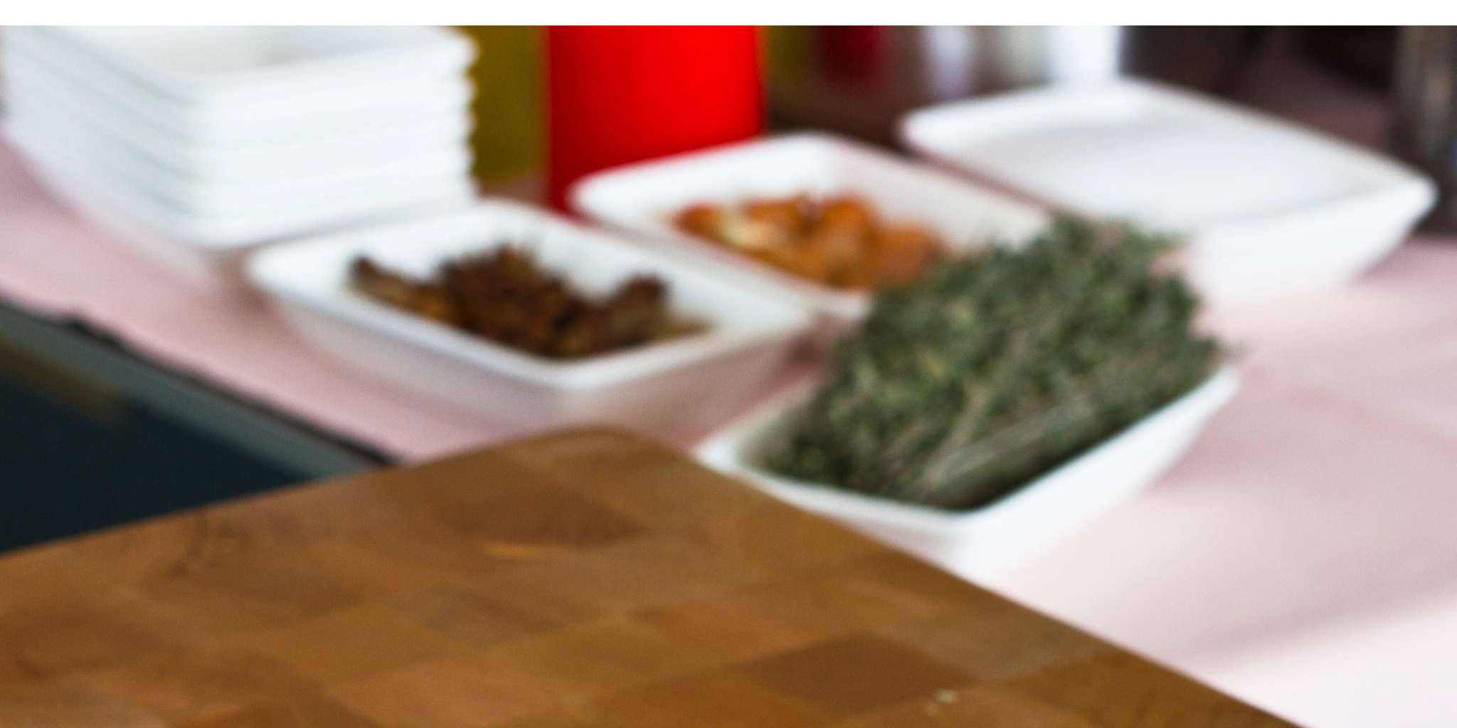 Butcher block table for cuting with kitchen visible and herbs in dishes.