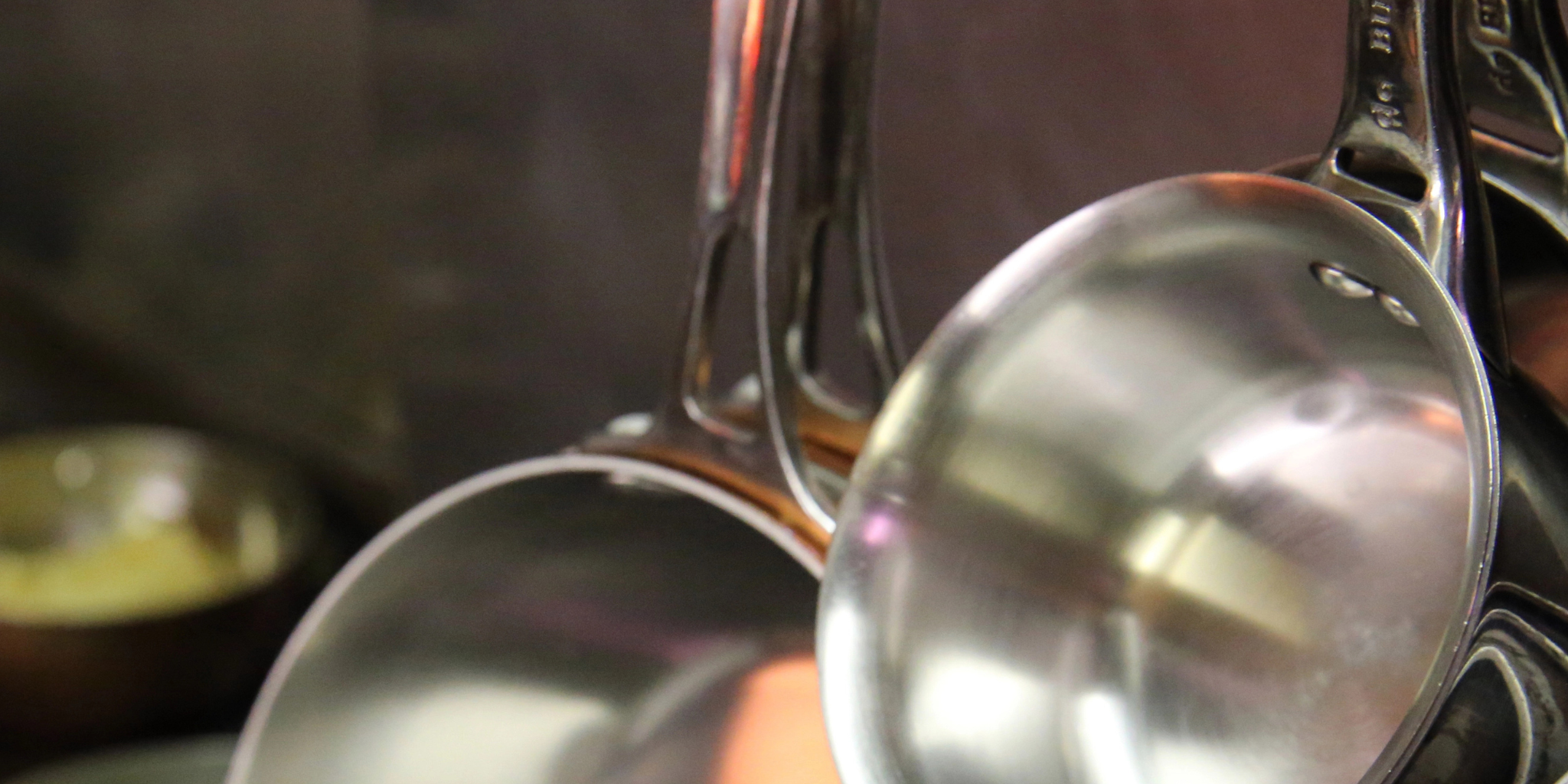 Stainless Pots hanging on pot rack with copper pots on stove below.